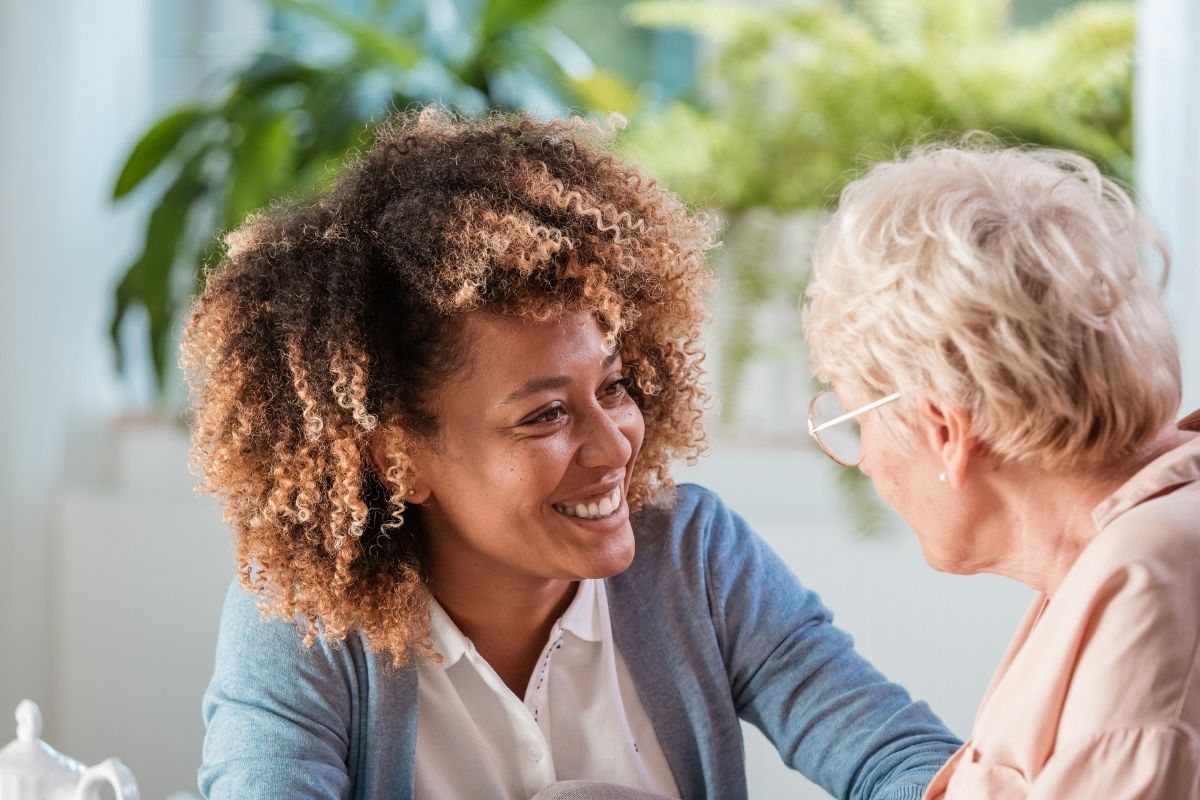 Support worker smiling and talking with an older woman at home