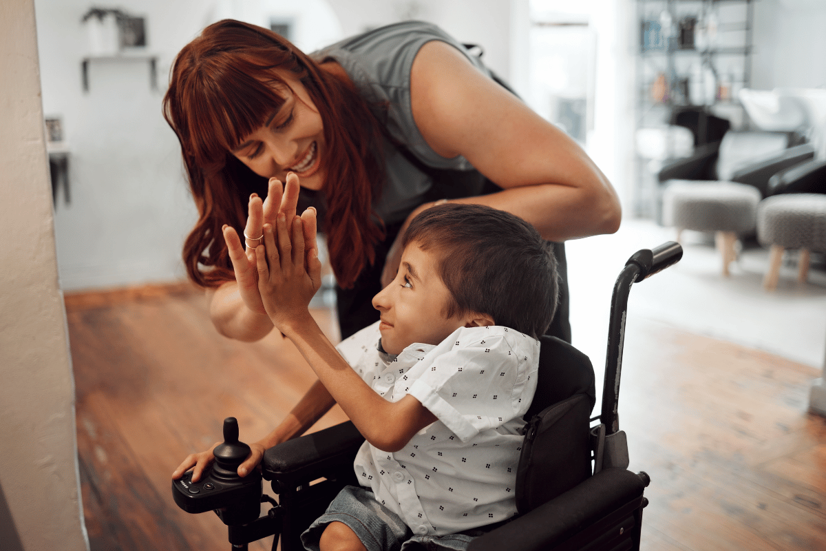 Support worker encouraging a child in wheelchair